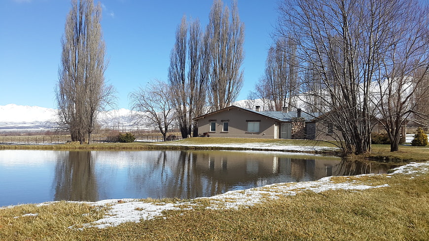 Rural house with pond and snow-capped mountains in spring
