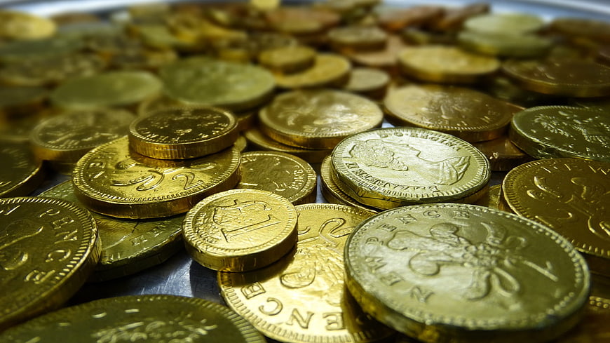 Close-up of scattered gold coins on a dark surface