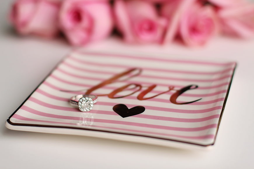 Diamond engagement ring on pink striped love plate with roses