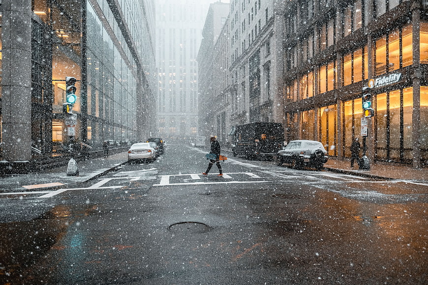 Pedestrian crossing snowy city street in winter