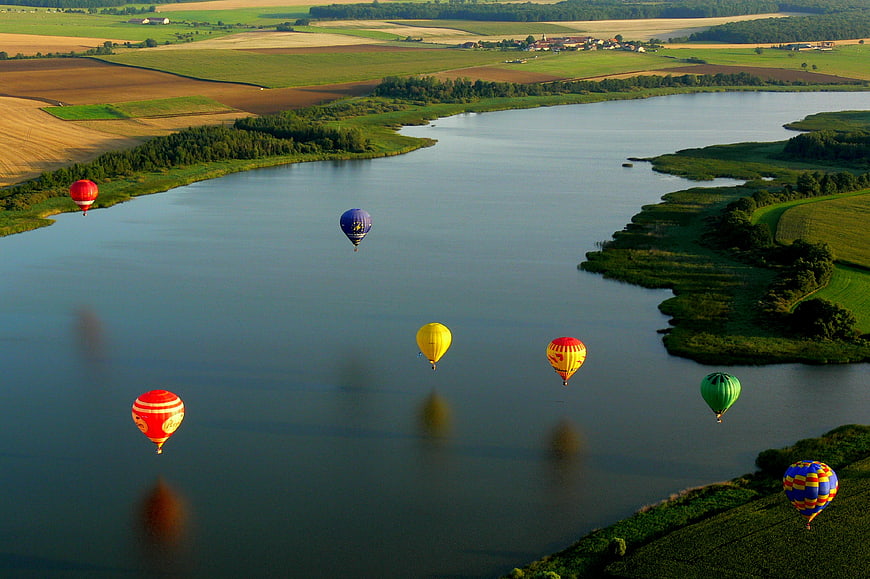 Aerial View of Colorful Hot Air Balloons Over River Landscape