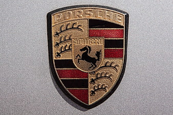 Close-up of Porsche emblem on silver car body