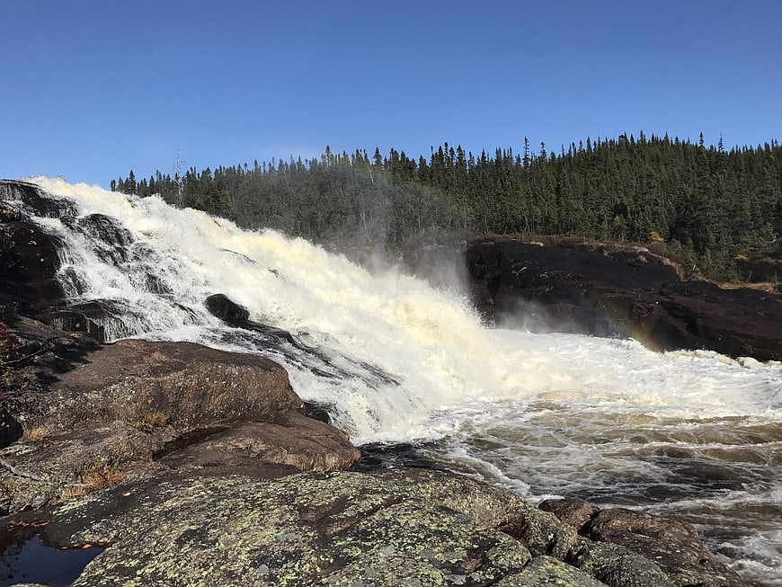 Powerful waterfall cascading over rocky cliffs into a river