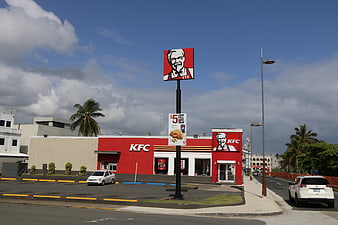 KFC Restaurant Exterior With Colonel Sanders Signage And Tropical Setting