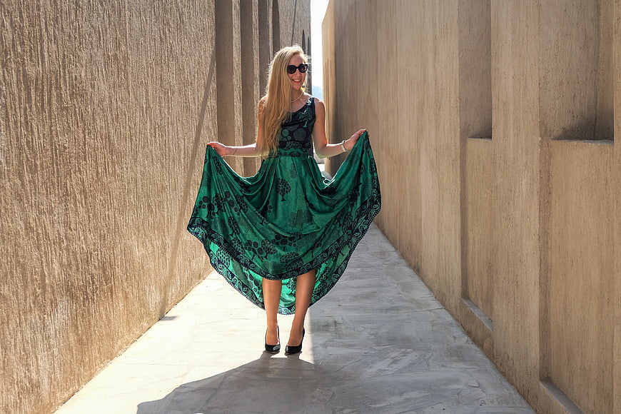 Blonde woman in green dress walking down narrow alley