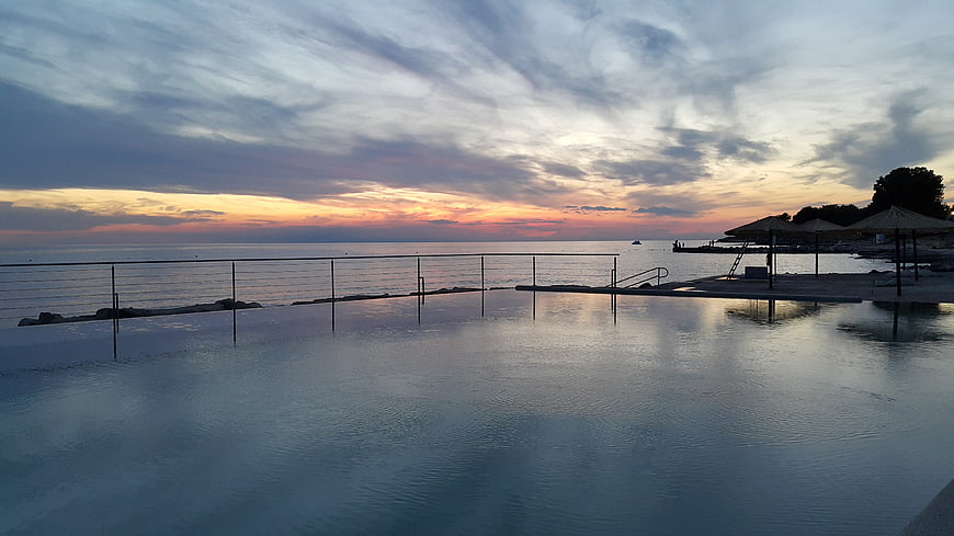 Serene infinity pool overlooking ocean sunset with dramatic clouds
