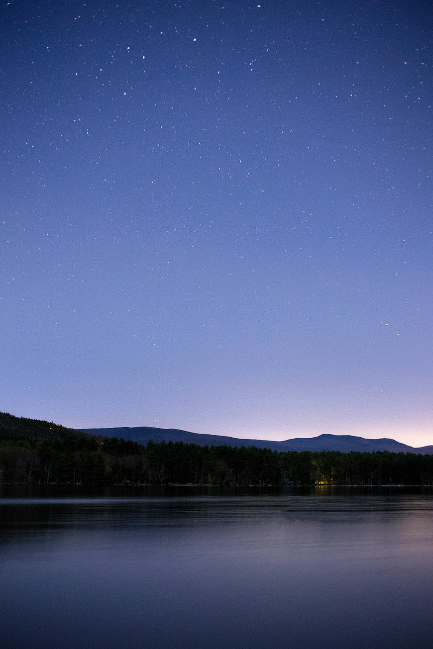 Starry Night Sky Over Lake and Mountain Silhouette