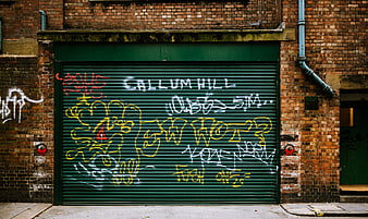 Green metal shutter with colorful graffiti on brick wall
