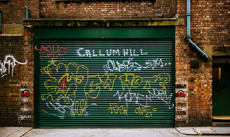 Green metal shutter with colorful graffiti on brick wall