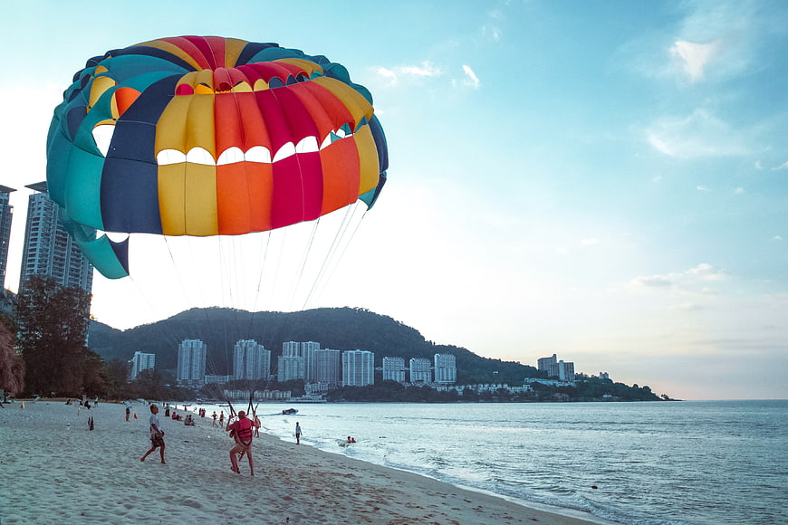 Colorful Parasailing Parachute on Tropical Beach with City Skyline