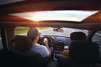Couple Driving Car with Sunroof at Sunset