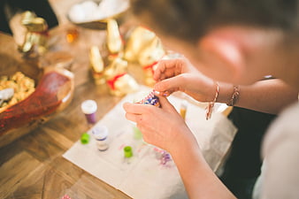 Close up of hands decorating Easter eggs with colorful sprinkles