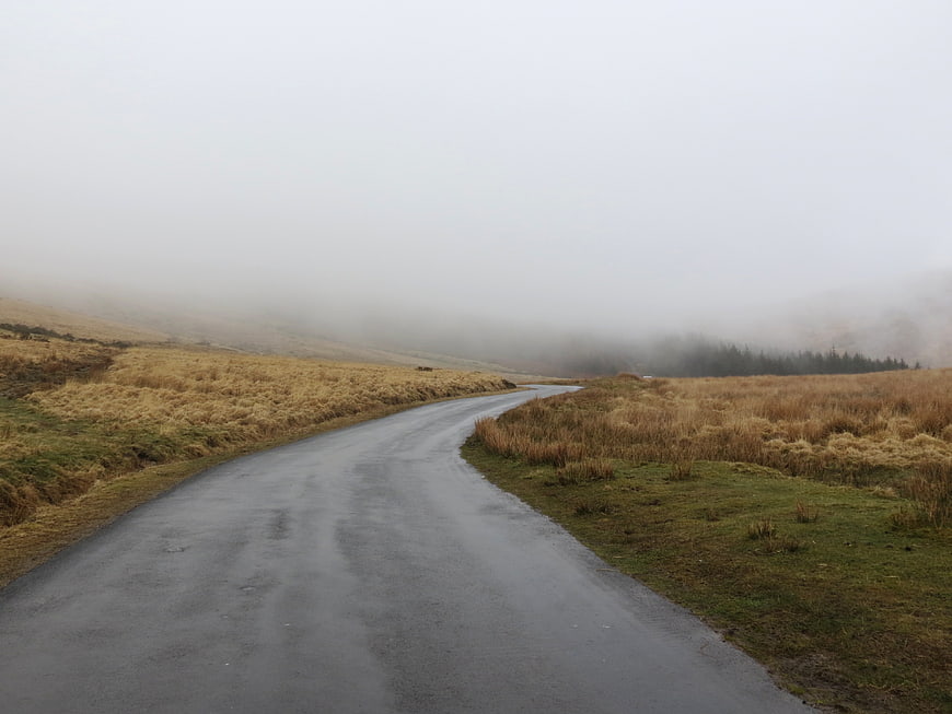 Winding wet road through foggy moorland landscape