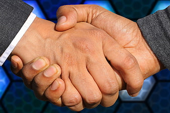 Close-up of a firm business handshake against a blue hexagonal background