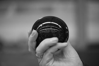 Hand holding black crystal ball with reflection