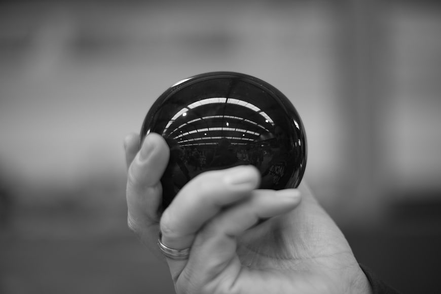 Hand holding black crystal ball with reflection