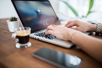 Woman Typing on Laptop with Coffee and Smartphone