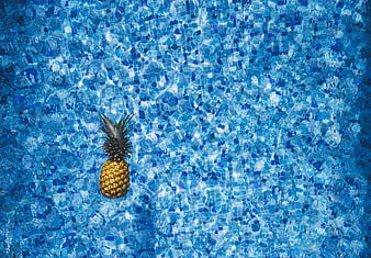 Pineapple floating in blue swimming pool water