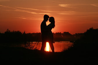 Silhouette of Romantic Couple Embracing at Sunset by Lake