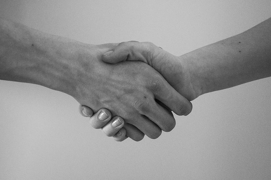 Black and White Handshake Close-Up on Gray Background