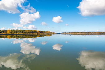 Serene Lake Reflection with Autumn Trees and Blue Sky