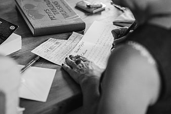 Woman writing wedding invitation by hand on wooden table