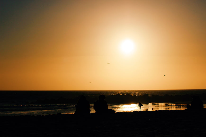 Silhouettes of People Watching Golden Sunset at Beach