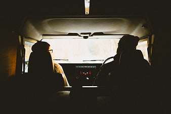 Silhouettes of two people driving in a van interior
