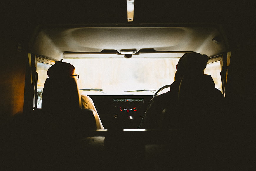 Silhouettes of two people driving in a van interior