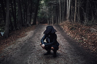 Woman in Black Leather Jacket Crouching on Forest Path