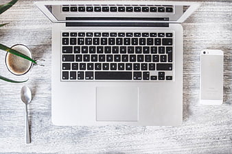 Flat lay of laptop, coffee, and smartphone on wooden desk