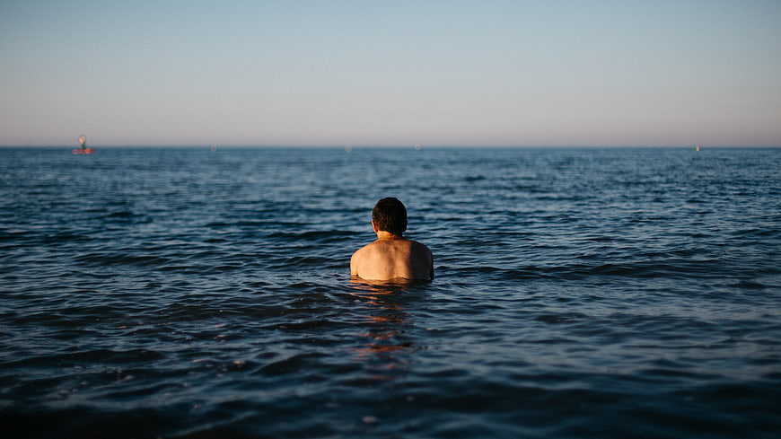 Man Swimming in Ocean at Sunset