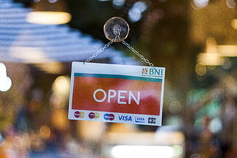 Open sign hanging on glass door with payment logos