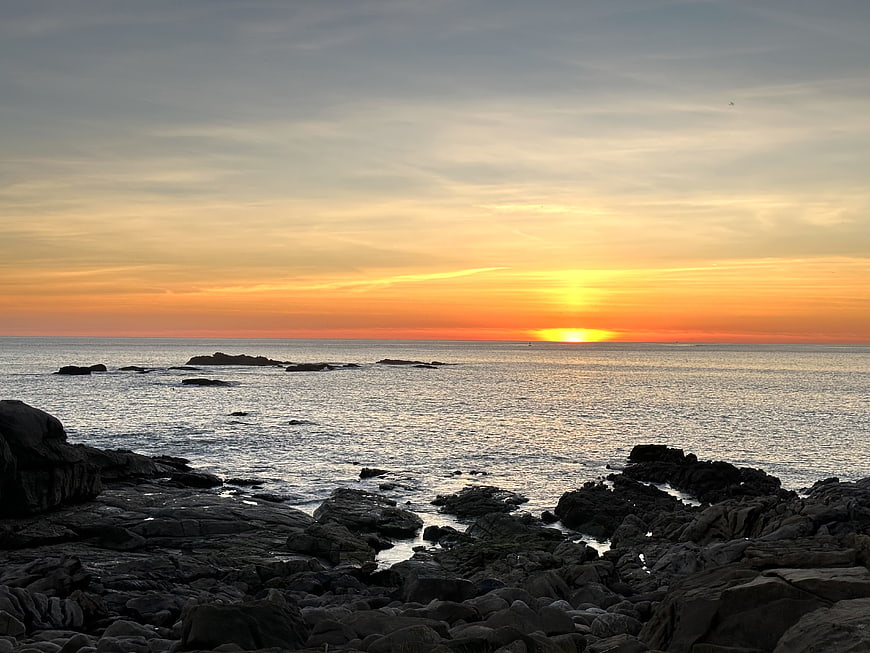 Serene Sunset Over Rocky Coastline with Golden Sky