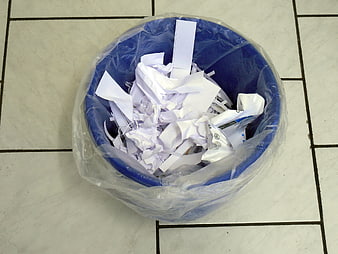 Blue recycling bin filled with shredded paper waste