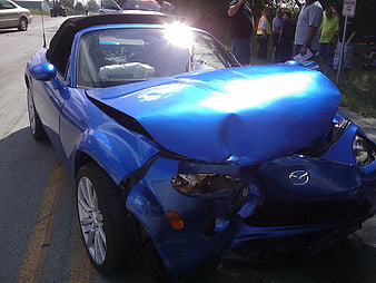 Blue Mazda Miata with severe front-end collision damage