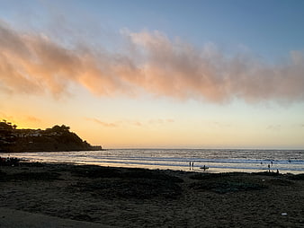 Sunset Beach Landscape with Surfers and Coastal Cliffs