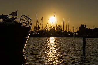 Silhouette of boats in harbor at golden sunset