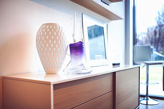 Modern interior decor with white and purple vases on wooden cabinet
