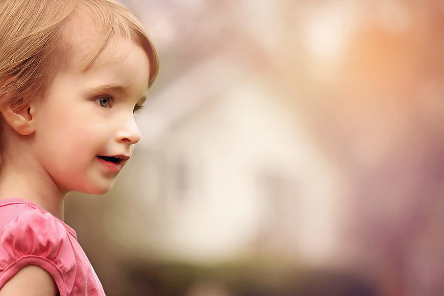 Close-up of a young girl in a pink shirt looking away
