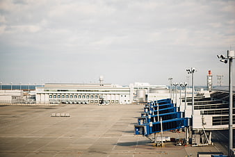 Wide view of airport tarmac with blue jet bridges and terminal