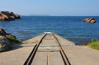 Old railway tracks leading into the blue ocean sea