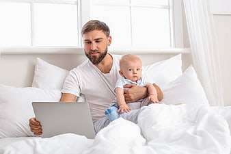 Father with Baby Using Laptop in Bed