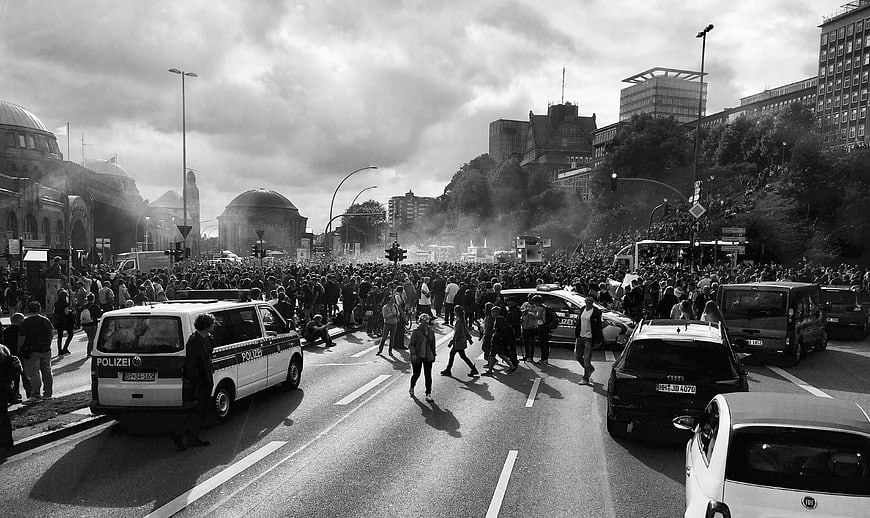 Black and white photo of a large protest crowd in a city street with police