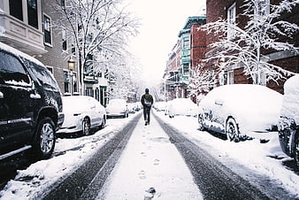 Man Walking Down Snow-Covered Urban Street