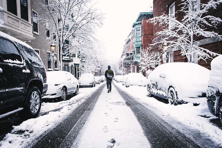 Man Walking Down Snow-Covered Urban Street