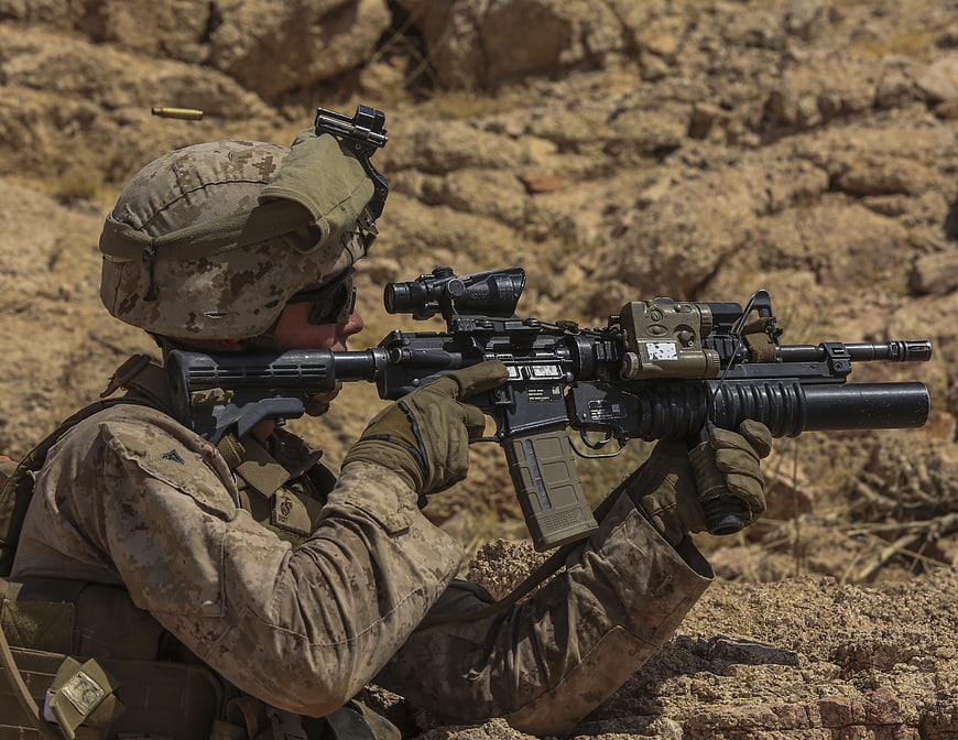 US Marine firing M4A1 carbine in desert terrain