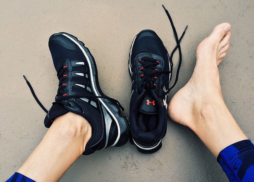 Black Running Shoes and Bare Feet on Concrete