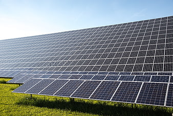 Large Solar Panel Array In Green Field Under Blue Sky