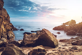 Dramatic Rocky Coastline at Sunset with Smooth Ocean Water